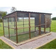 a small chicken coop in the middle of a grassy area with gravel and grass around it