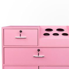 a pink dresser with three drawers and two knobs on each drawer, against a white background