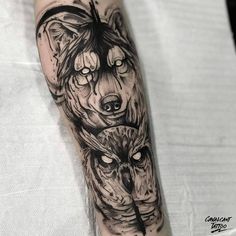 a black and white tattoo on the arm of a woman with two wolfs behind her