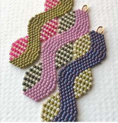 four pieces of beaded jewelry sitting on top of a white cloth covered table next to each other