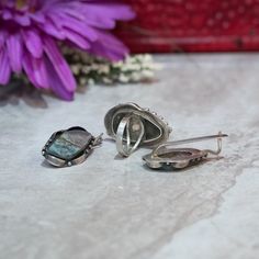 "This beautiful piece is handcrafted with exquisite detailing and features a genuine mottled blue-grey Agate stone that measures 1.5\" long and almost 1\" at its widest point. This measurement includes the solid sterling setting with its studded and gently curved ribbon-like design. The band fits a US size 10 finger and cannot be re-sized as the stone is already set (though you may order a custom ring). This ring is one of a kind and has matching earrings to go with it. The earrings measure 1.25 Silver Agate Jewelry With Matching Earrings, Handmade Gray Round Jewelry, Unique Gray Jewelry As Gift, Unique Gray Jewelry For Gifts, Unique Gray Jewelry For Gift, Handmade Jewelry Set, Grey Agate, Band Fits, Earrings Geometric