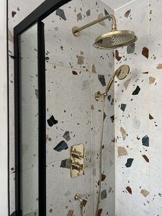 a shower head and hand held shower faucet in a bathroom with mosaic tiles on the walls