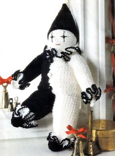 a crocheted black and white doll next to bells