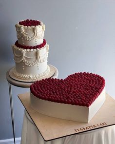 a heart shaped cake sitting on top of a table next to a white and red wedding cake