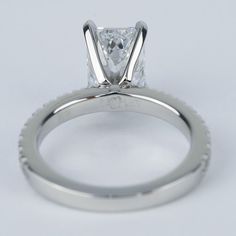 a white gold ring with a princess cut diamond in the center, on a plain surface