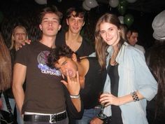 a group of young people standing next to each other at a party with balloons in the background