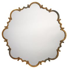 a mirror that is sitting on top of a white surface with gold trimmings