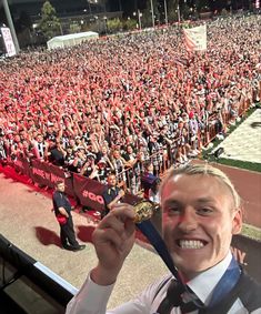 a man holding up a medal in front of a large group of people at an event