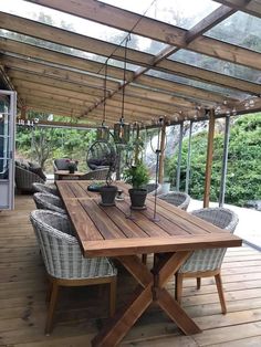 a wooden table sitting on top of a wooden floor next to a glass roof covered patio