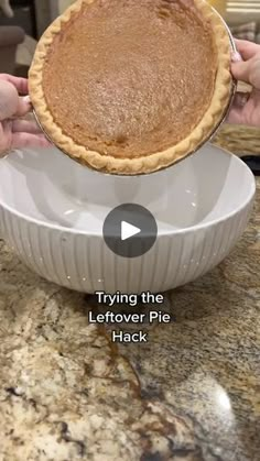 a person holding a pie in a white dish on top of a counter with the text trying the leftover pie hack