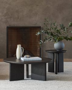 a table with two vases and a book on it in front of a fireplace