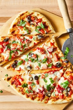 sliced pizza on cutting board with spatula and knife