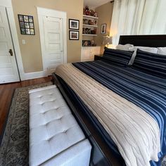 a bedroom with a bed, ottoman and pictures on the wall