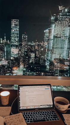 an open laptop computer sitting on top of a desk next to a cup of coffee