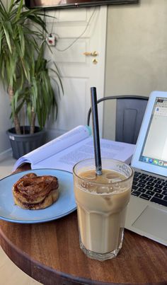 a laptop computer sitting on top of a wooden table next to a cup of coffee