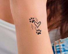 a woman with a tattoo on her arm and paw prints in the shape of a heart