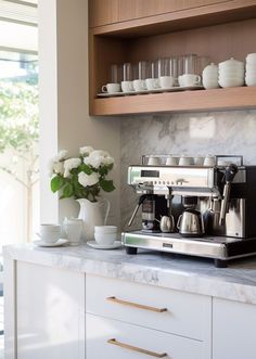 a coffee maker and cups on a counter in a kitchen