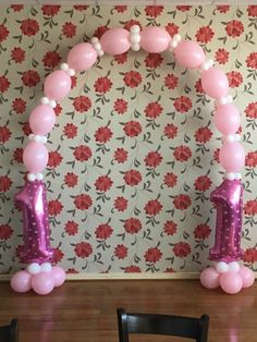 balloon arch with pink and white balloons in front of floral wallpaper