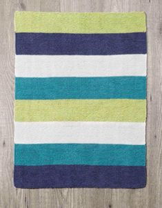 a blue, green and white striped rug sitting on top of a wooden floor