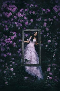 a woman standing in front of a window surrounded by flowers