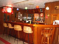 a bar with several stools and lights hanging from the ceiling