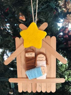 a wooden ornament with two dolls hanging from it's side on a christmas tree