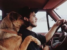 a man driving a car with his dog on his lap