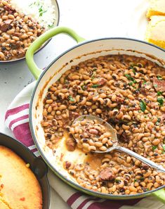 a pot filled with beans and meat on top of a table next to other dishes