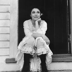 black and white photograph of a woman sitting in front of a door