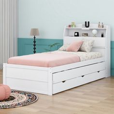 a white bed with drawers underneath it and a rug on the floor next to it