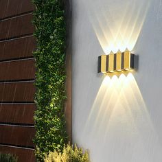 a wall mounted light on the side of a building next to a potted plant