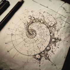 a spiral drawing on top of a piece of paper next to a pen and ink