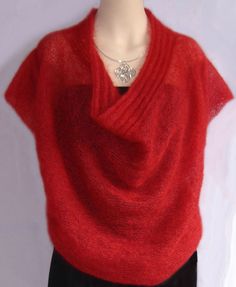 a mannequin wearing a red knitted shawl with a diamond brooch