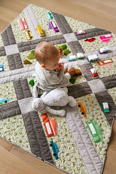 a baby is sitting on the floor playing with his stuffed animal and toy car blocks