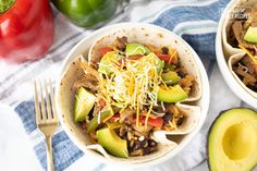 two white bowls filled with taco salad next to an avocado