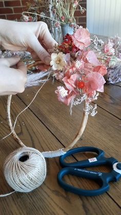 someone is making a flower arrangement out of twine and yarn on a wooden table