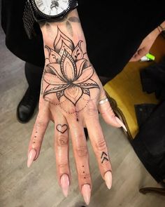 a woman's hand with tattoos on it and a wrist watch in the background