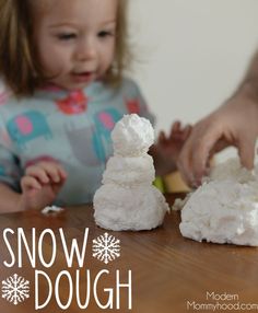 a baby playing with snow dough on a table