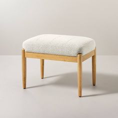 a wooden bench with a white upholstered seat and back rest on a plain surface