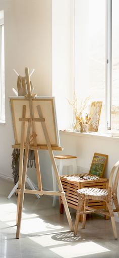 an easel sitting next to a window in a room with sunlight coming through the windows