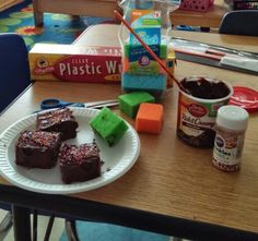 some brownies are sitting on a paper plate next to plastic containers and other items