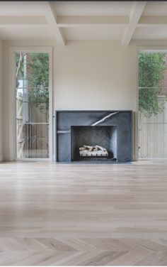 an empty room with a fireplace and large windows