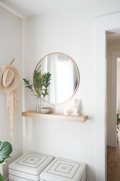 there is a mirror on the wall above two stools and a potted plant