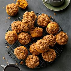 muffins cooling on a wire rack next to a cup of coffee and saucer