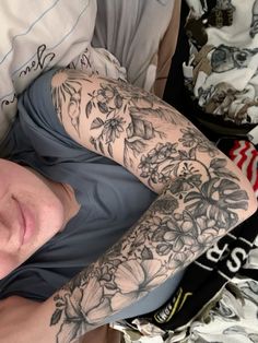 a man laying in bed with his arm covered by flowers and butterflies on the sleeve