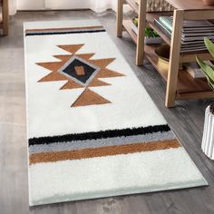 a white rug with an orange, brown and black design on the floor in a living room