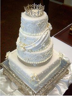 a three tiered white wedding cake with a crown on top is sitting on a table