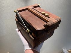 a person holding a small wooden box with writing utensils in it's compartment