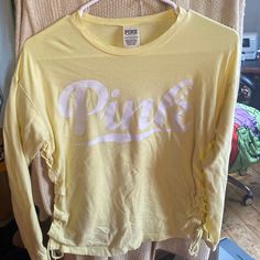 Never Worn Pale Yellow Victoria’s Secret Longsleeve Shirts Has Pink Written Down The One Sleeve Along With Lattice Tie Sides Pink Letter Print Top By Victoria's Secret, Victoria's Secret Pink Tops With Letter Print, Victoria's Secret Pink Letter Print Top, Trendy Victoria's Secret Cotton Tops, Trendy Victoria's Secret Crew Neck Top, Victoria's Secret Trendy Cotton Tops, Victoria's Secret Long Sleeve Tops For Summer, Trendy Cotton Tops By Victoria's Secret, Victoria's Secret Long Sleeve Summer Tops