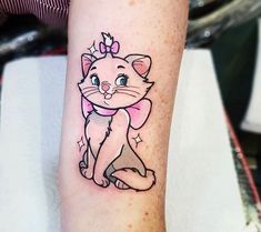 a cat with a bow on it's head is sitting on the arm and has a pink ribbon around its neck